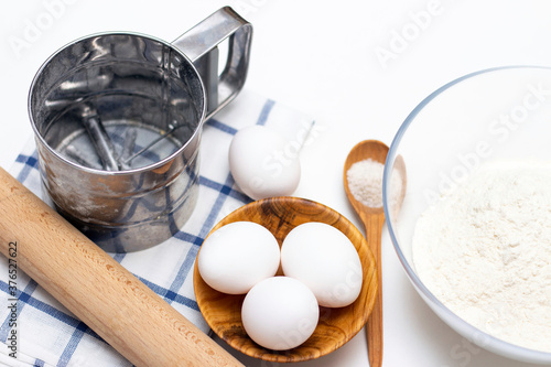 making dough for bread or homemade baked goods. ingredients on the table: eggs, flour, salt, rolling pin