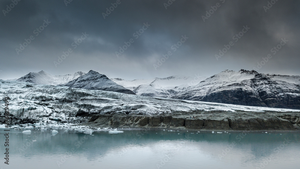 Fototapeta premium edge of the glacier from the boat with mountains in the back