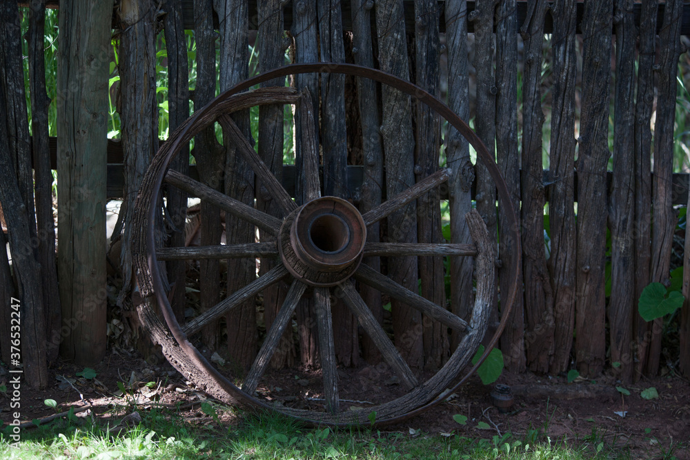 Old wagon wheel leaning against a fence