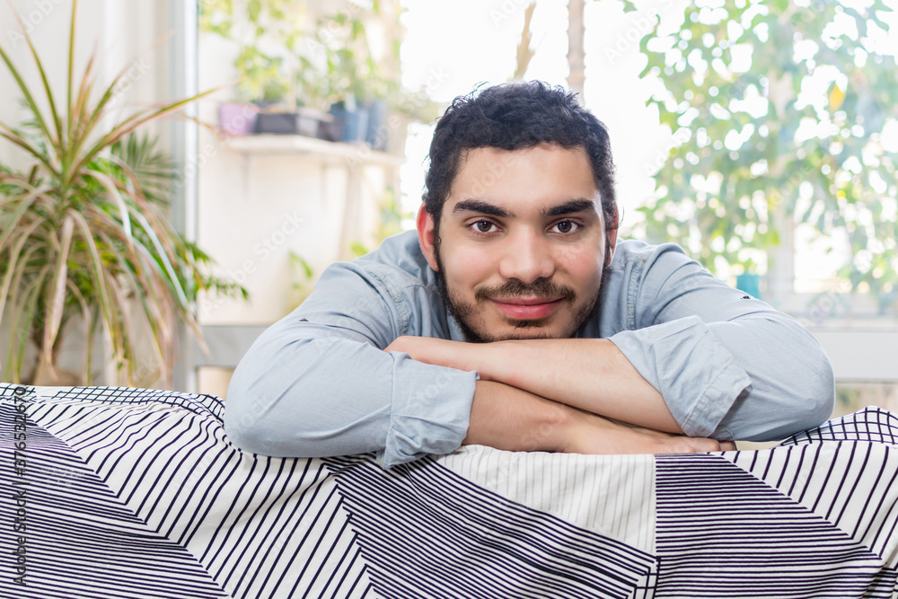 smiling young man looking at camera, sitting on the sofa smiling young man looking at camera, sitting on the sofa