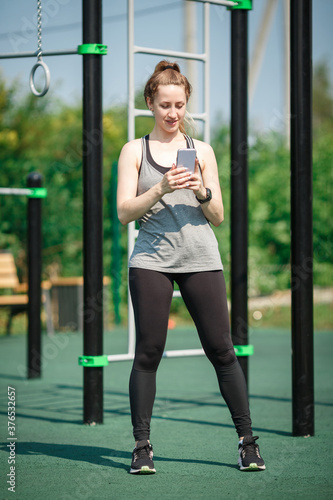 Young fitness woman taking a workout rest for texting on her smartphone . Healthy modern lifestyle and sport concept.