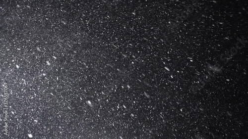 A dense heavy blizzard snowstorm VFX insert in slow-motion on a black screen. Black screen Christmas snowstorm. Particles swirling moved by wind. Snow is moving through space. Snowstorm on black. photo