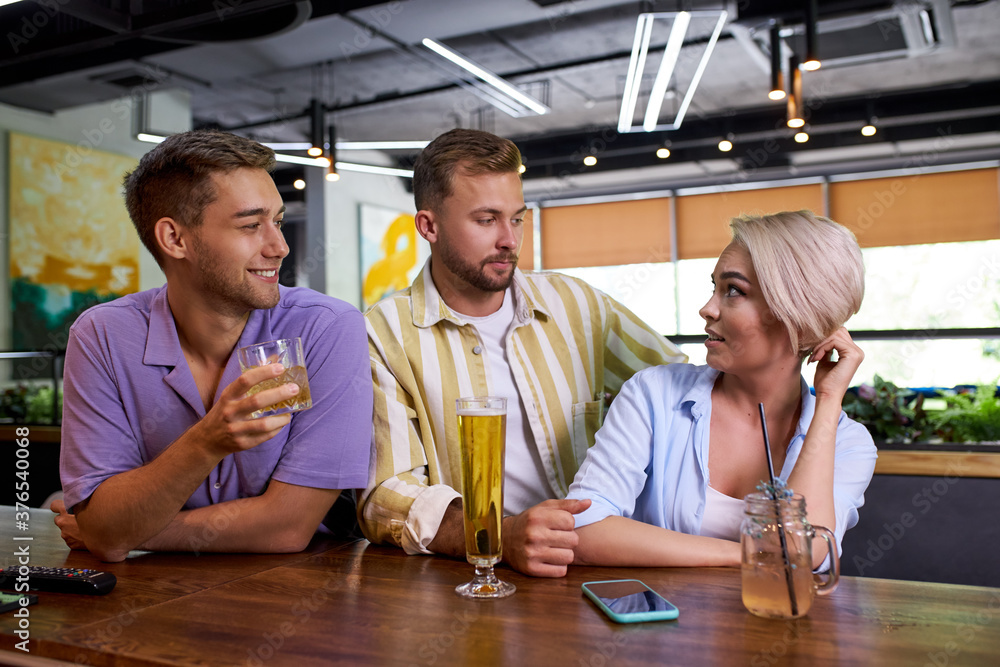 portrait of three young people having fun, talk and flirt in the bar. beautiful caucasian people spend weekends not at home portrait of three young people having fun, talk and flirt in the bar. beautiful caucasian people spend weekends not at home