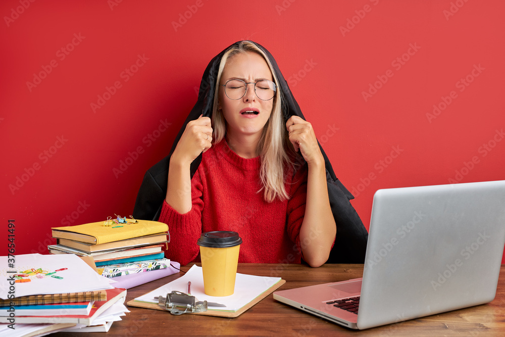 young beautiful sad and depressed caucasian manager working in stress at office computer desk feeling overwhelmed and frustrated suffering headache and depression isolated over red background.. young beautiful sad and depressed caucasian manager working in stress at office computer desk feeling overwhelmed and frustrated suffering headache and depression isolated over red background..