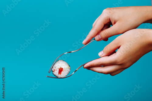 how to eat sushi roll with a fork  isolated on blue background. How to eat sushi without chopsticks