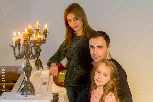 Happy Family Posing near Piano Decorated with Burining Candles