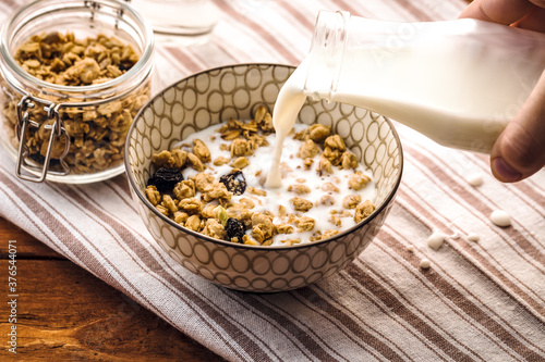 Breakfast food background. Milk Pouring Over Granola on light table napkin, Healthy vegetarian breakfast. Diet Nutrition Concept
