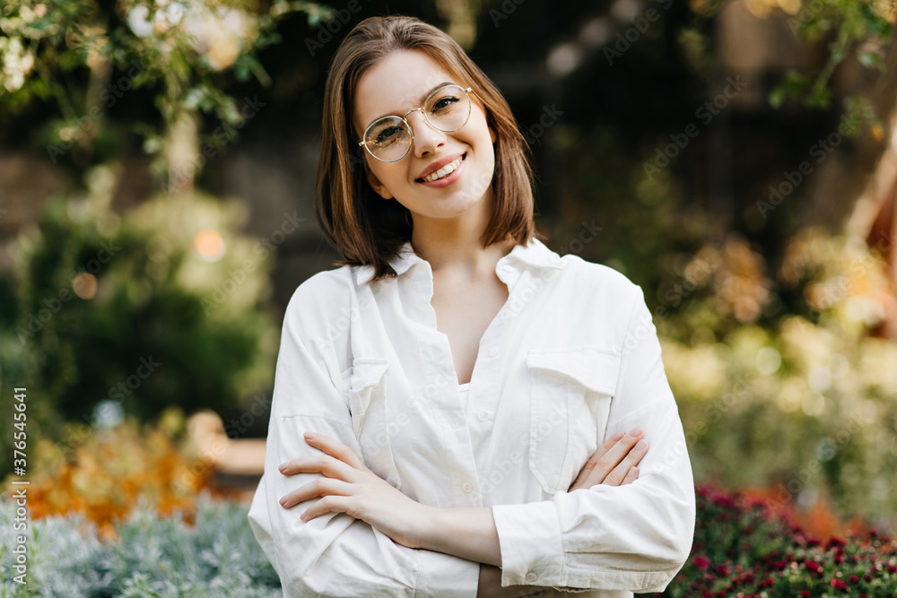 Pleasant caucasian girl standing on blur nature background. Laughing merry woman posing in garden. Pleasant caucasian girl standing on blur nature background. Laughing merry woman posing in garden.