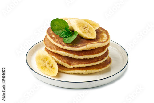 Stack of pancakes with banana and mint leaf on dish over white