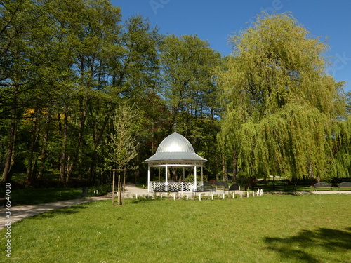 Small white bandstand surrounded by green trees, Oruński Park, Gdansk, Poland