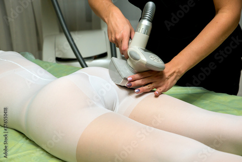 Woman in white suit getting LPG anti cellulite massage in a beauty SPA salon.