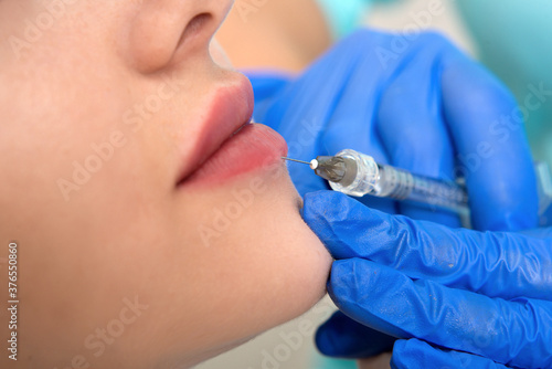 cosmetologist making injection in face  lips.