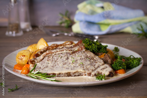 Roast beef steak fillets with creamy Gorgonzola cheese dressing and vegetables on plate. Horizontal photo