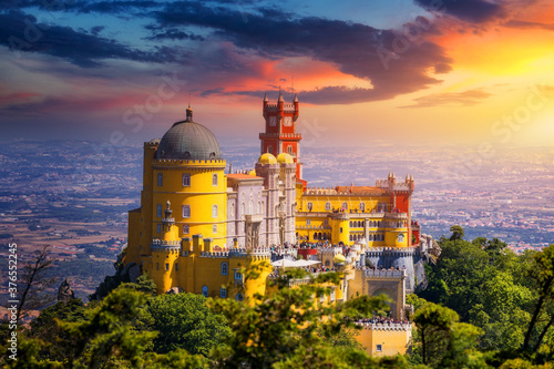 Famous historic Pena palace part of cultural site of Sintra against sunset sky in Portugal. Panoramic View Of Pena Palace, Sintra, Portugal. Pena National Palace at sunset, Sintra, Portugal. photo