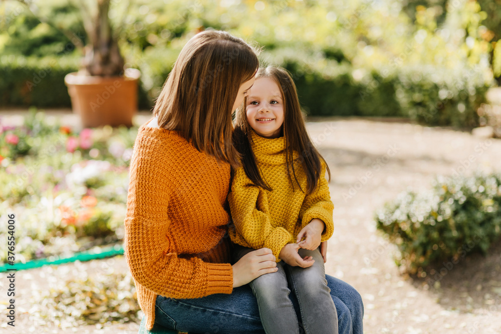 Smiling kid sitting on mother's knees. Woman resting in park with little daughter. Smiling kid sitting on mother's knees. Woman resting in park with little daughter.