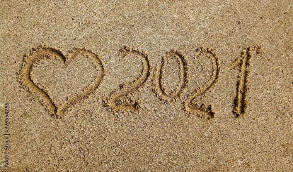 Fototapeta premium The concept of a New year. Heart and numbers 2021 in the sand. Summer beach holidays . The message is handwritten