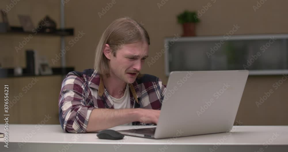 Young man plays a game on the computer, looses, gets upset, screams and cries Young man plays a game on the computer, looses, gets upset, screams and cries