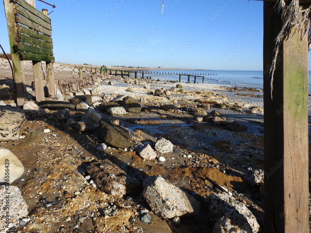 A view of the beach and the sea and numerous remnants of concrete and metal - A beach with a mess