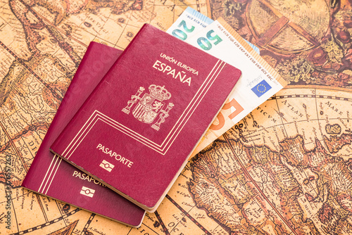 Spanish passport with euro bills inside, on a world map for travelers. photo