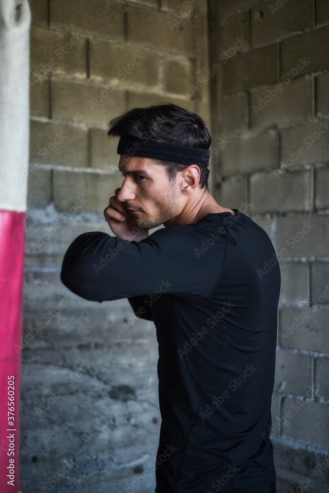 A handsome man in a black shirt punching a boxing bag
