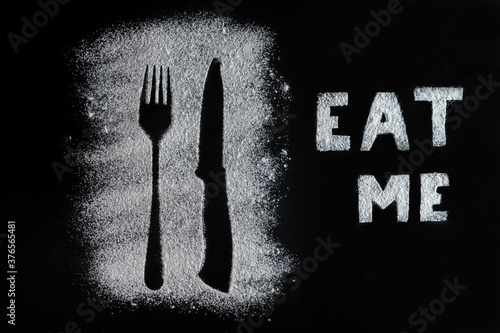 Fork and knife silhouette made with flour. eat me flour inscription.