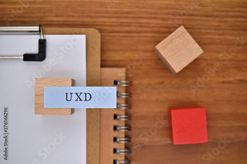 The words "UXD" written on sticky note with clipboard in diagonal angle.