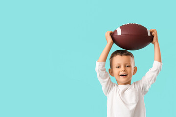Little boy with rugby ball on color background