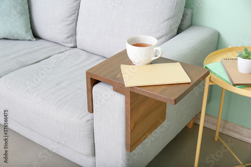 Foto Cup of tea with notebook on armrest table in room