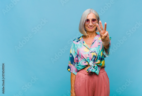 Schilderij op canvas middle age cool woman smiling and looking friendly, showing number three or thir