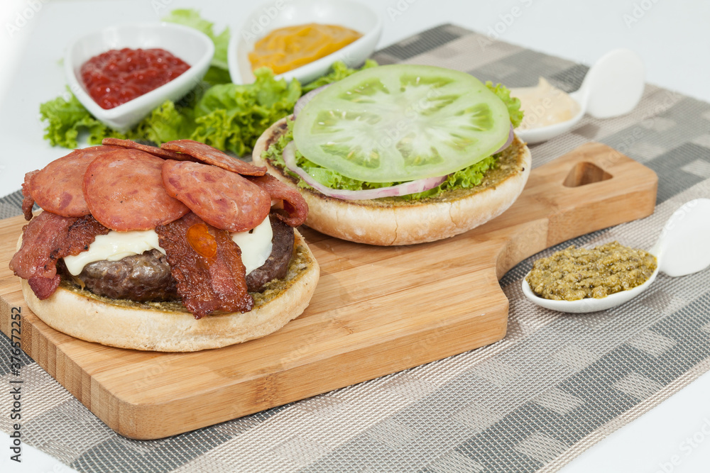 Slice Of Hamburger Bun With Salami, meat, And Sauce; Ready To Assemble The Burger. Slice Of Hamburger Bun With Salami, meat, And Sauce; Ready To Assemble The Burger.