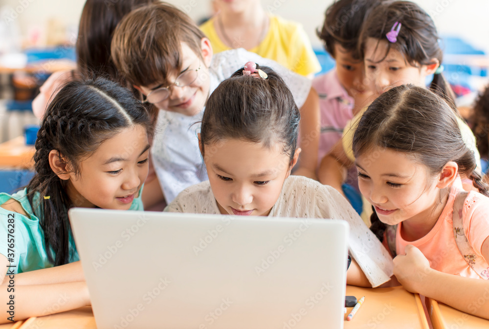 Happy children watching the laptop in the classroom Happy children watching the laptop in the classroom