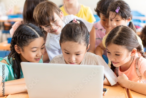 Happy children watching the laptop  in the classroom