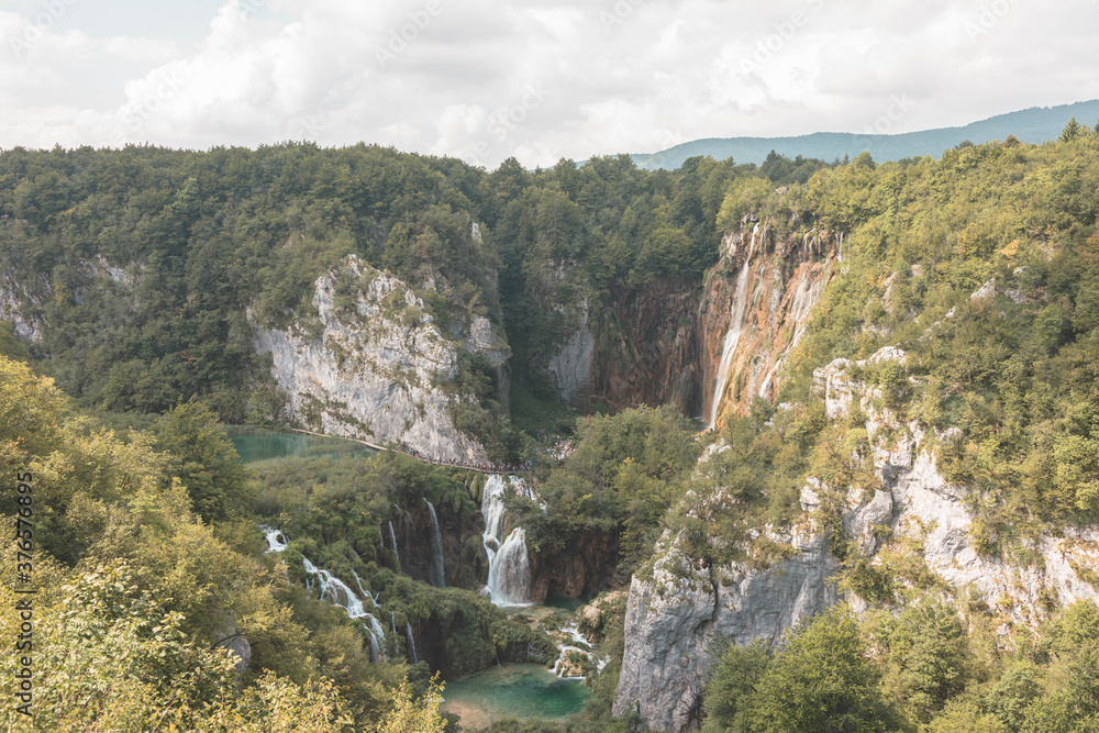 Plitvice Lakes National Park in Croatia. Breathtaking waterfalls view of beautiful wild green lake. Rocky walls of mountains flank the wild natural fortress, isolating it by rest of landscape.