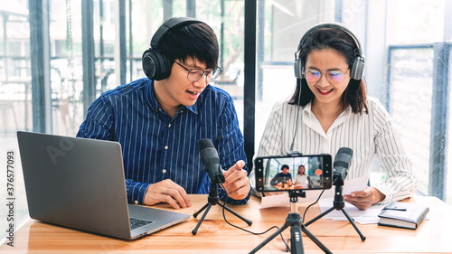 Foto Asian Man and woman podcasters in headphones recording content with colleague ta