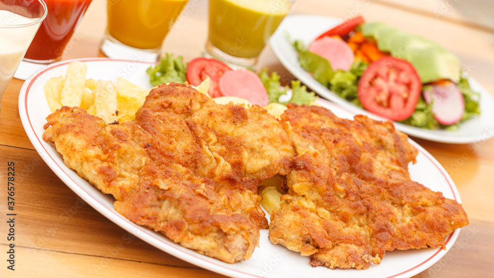 chicken milanesa with french fries and salad - peruvian food chicken milanesa with french fries and salad - peruvian food