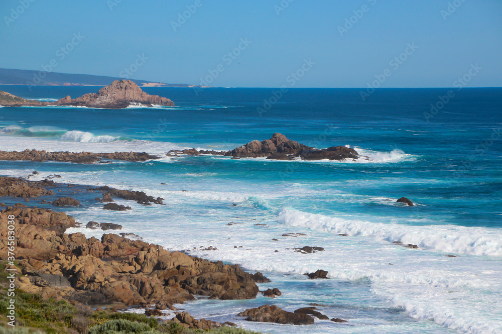 Scenic ancient Sugar Loaf Rock South Western Australia in the blue Indian Ocean is a popular fishing and hiking destination with its treeless green dunes and splashing waves on old eroded rocks. Scenic ancient Sugar Loaf Rock South Western Australia in the blue Indian Ocean is a popular fishing and hiking destination with its treeless green dunes and splashing waves on old eroded rocks.