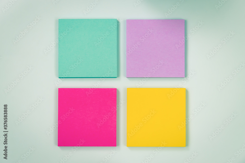4 Color Stick Note or Note Pad as Green,Purple,Pink,Yellow on Modern Clean Creative Office Desk or Office Table on Top View. Office Supplies on Blue Pastel Minimalist Background in Vintage Tone
