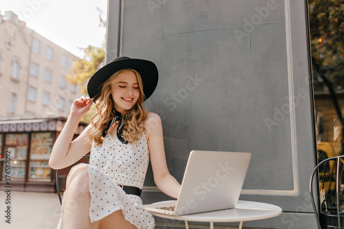 Tableau sur toile Romantic blonde in black hat with wide brim, in elegant white dress and black sc