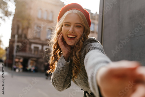 Photography Attractive girl in red hat smiling, looking into the camera, pulling her hand an