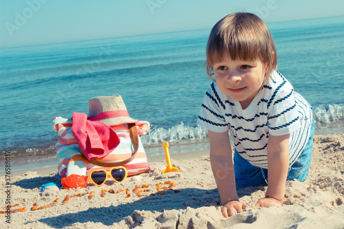 Baby boy playing on sand at summer beach. Vacation time and child development concept