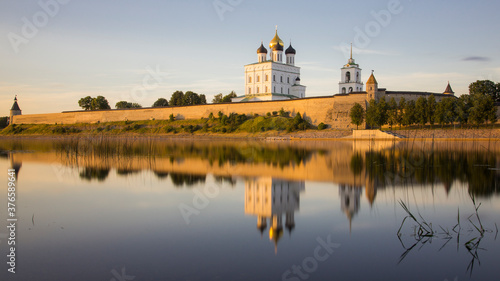Pskov Kremlin and Troitsky Cathedral at sunrize reflected in still river water