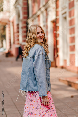 vertical photo of a blond trendy young girl who is turning round and looking into the camera