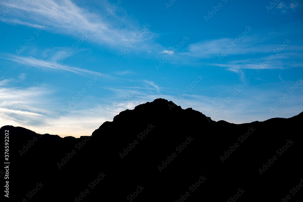 Silhouette of a mountain range against a vivid blue sky