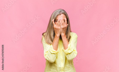 middle age pretty woman covering eyes with one hand feeling scared or anxious, wondering or blindly waiting for a surprise photo