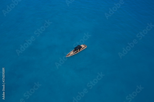 luxury motor boat. Drone view of a boat. Lonely boat mooring on the water. Top view of a white boat in the blue sea. Aerial view of a yacht on blue water. © Berg