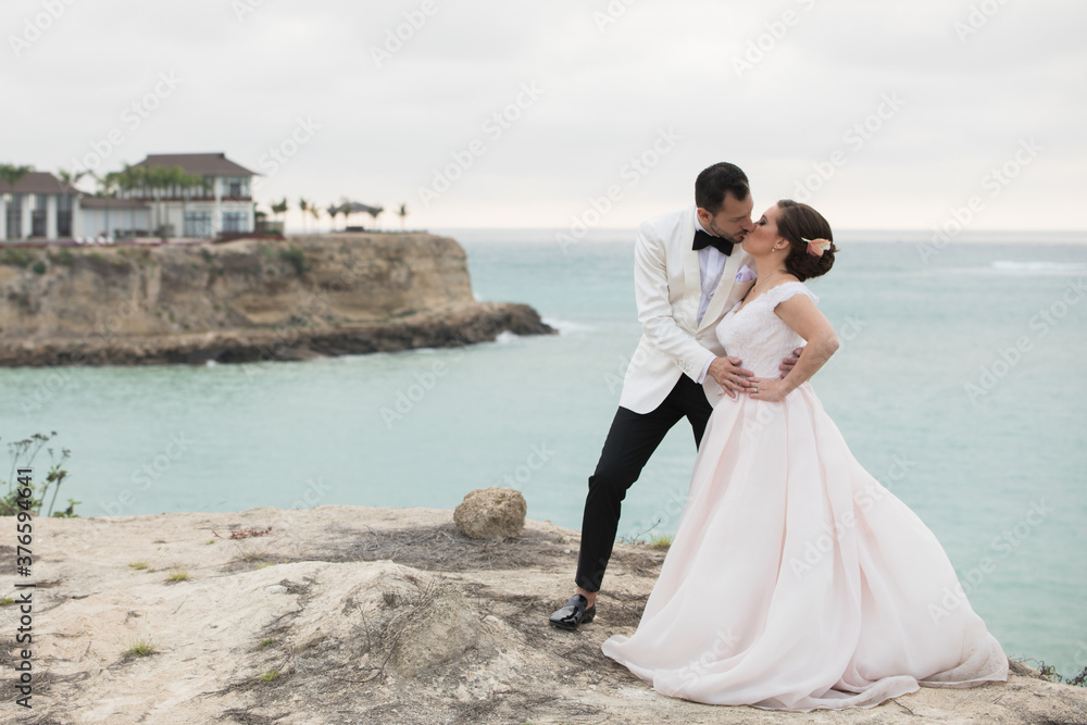 Latino bride and groom kissing near a cliff Latino bride and groom kissing near a cliff