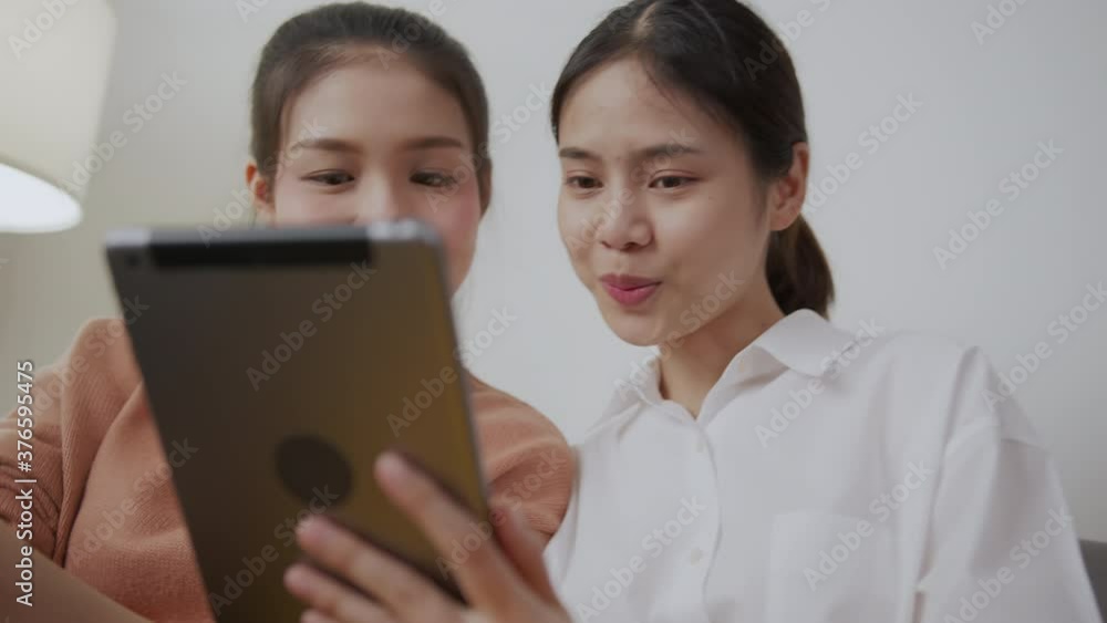 Cheerful beautiful Asian with friends sitting on sofa and using smartphone and tablet on social media. Cheerful beautiful Asian with friends sitting on sofa and using smartphone and tablet on social media.