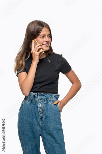Studio shot of  smiling teenager girl with braces  speaking by phone, isolated