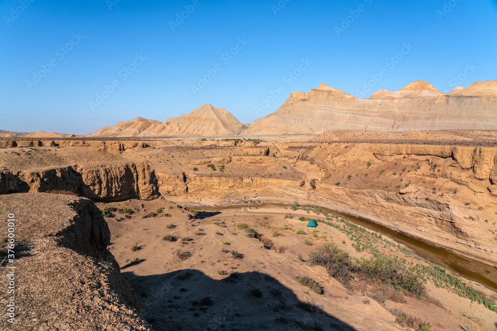 Fototapeta premium Tourist tent in a mountainous desert area by a small river