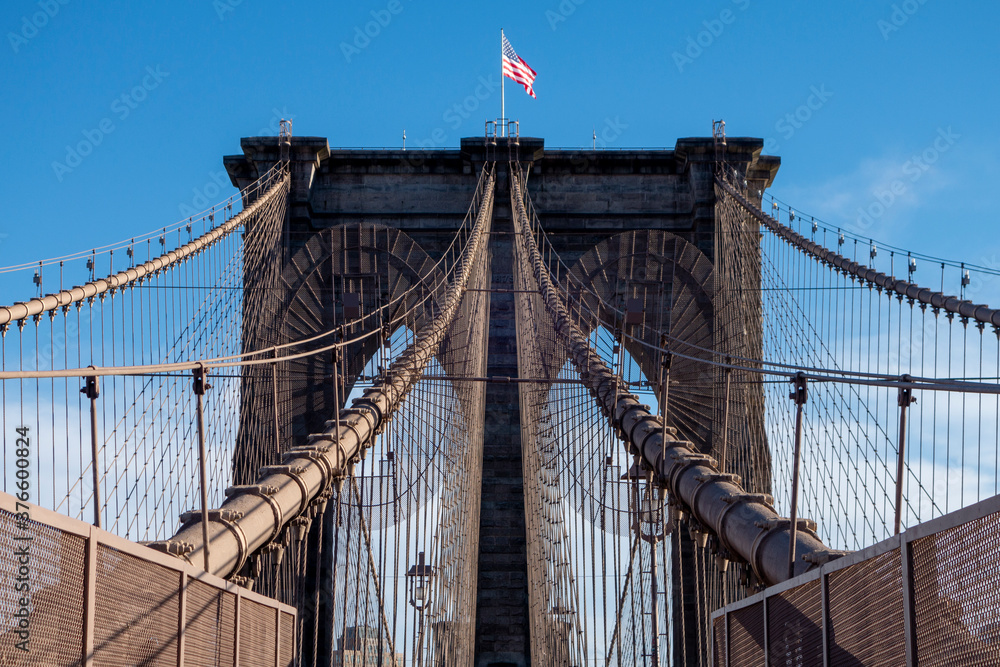 Fototapeta premium New york city manhattan to brooklyn bridge with use flag on top sand suspension cables